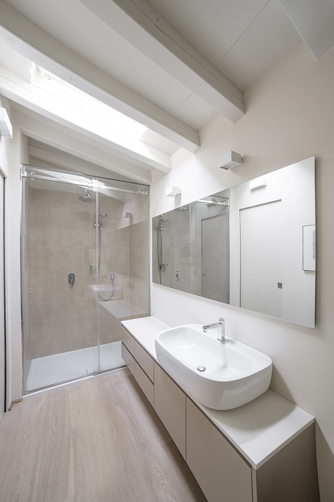 Idéer för ett litet modernt en-suite badrum, med släta luckor, grå skåp, grå kakel, porslinskakel, vita väggar, ljust trägolv, ett fristående handfat, bänkskiva i akrylsten, en dusch i en alkov och dusch med skjutdörr
