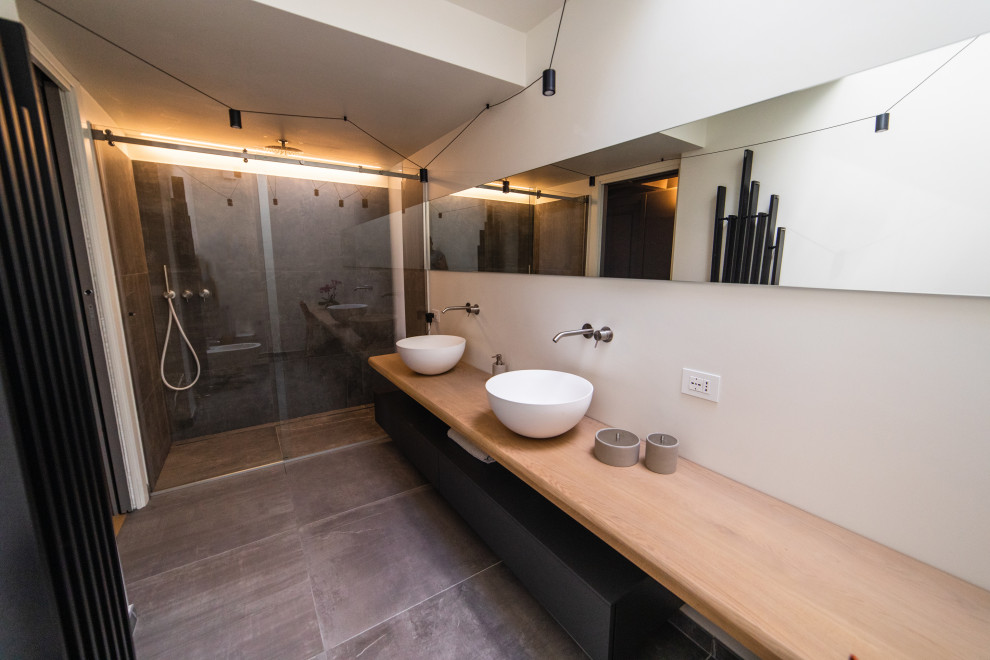 Example of a large trendy 3/4 white tile porcelain tile, gray floor, double-sink and coffered ceiling bathroom design in Other with beaded inset cabinets, black cabinets, a wall-mount toilet, white walls, a vessel sink, wood countertops, brown countertops and a floating vanity