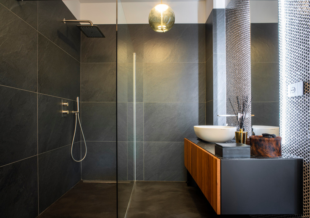 Modernes Badezimmer mit flächenbündigen Schrankfronten, hellbraunen Holzschränken, bodengleicher Dusche, grauen Fliesen, Aufsatzwaschbecken, grauem Boden, offener Dusche, schwarzer Waschtischplatte, Einzelwaschbecken und schwebendem Waschtisch in Turin