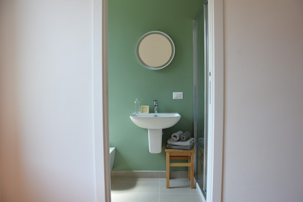 Cette image montre une petite salle de bain design avec WC séparés, un mur vert, un sol en carrelage de porcelaine, un lavabo suspendu, un sol gris et une cabine de douche à porte coulissante.