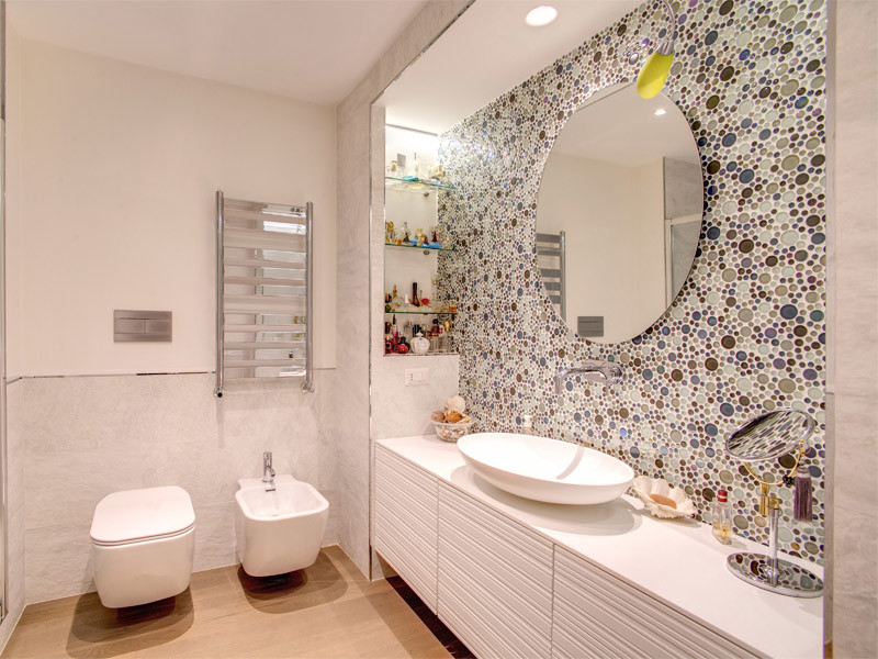 Idée de décoration pour une salle de bain design avec WC suspendus, un carrelage multicolore, des plaques de verre, un mur multicolore, parquet clair, une vasque et un sol beige.