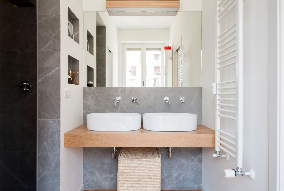 На фото: ванная комната в современном стиле с серой плиткой, белыми стенами, паркетным полом среднего тона, настольной раковиной, столешницей из дерева, коричневым полом, бежевой столешницей, нишей и тумбой под две раковины с