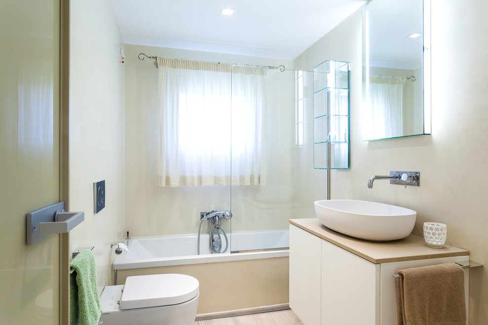 На фото: ванная комната среднего размера в современном стиле с плоскими фасадами, белыми фасадами, ванной в нише, бежевыми стенами, светлым паркетным полом, настольной раковиной, столешницей из дерева и открытым душем с