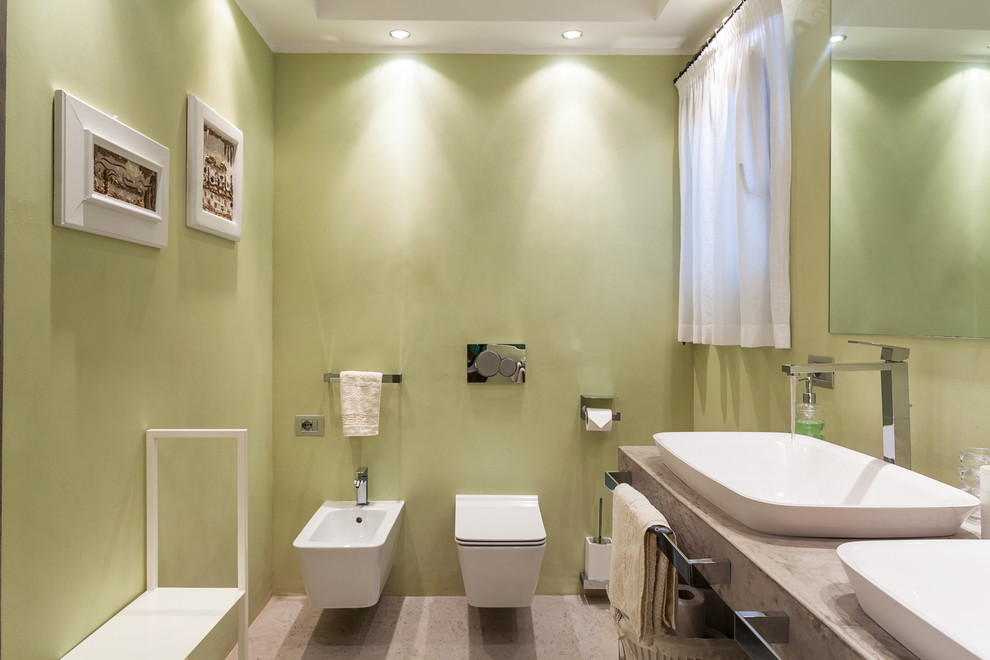 Imagen de cuarto de baño de obra actual de tamaño medio con sanitario de pared, paredes verdes, lavabo sobreencimera y encimera de mármol