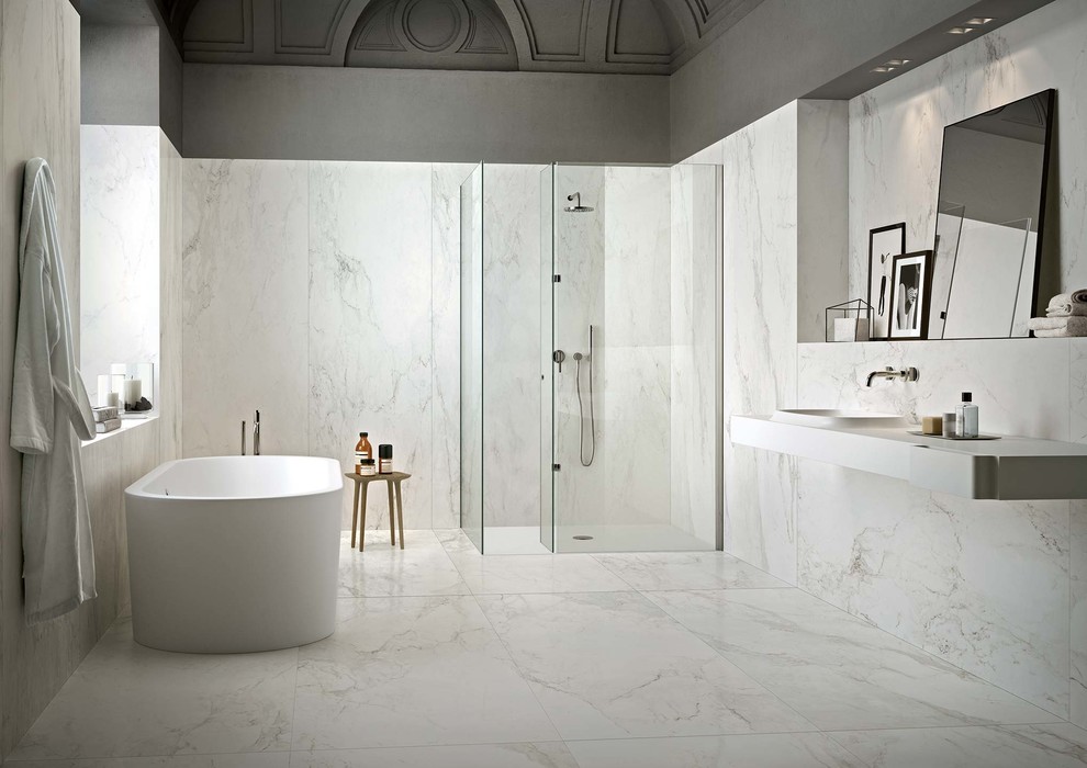 Modern inredning av ett stort vit vitt badrum med dusch, med ett fristående badkar, en kantlös dusch, vit kakel, porslinskakel, grå väggar, klinkergolv i porslin, ett integrerad handfat, vitt golv och dusch med gångjärnsdörr