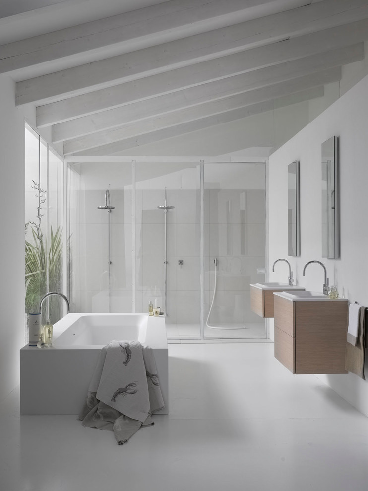 Cette image montre une petite salle d'eau minimaliste en bois clair avec un placard à porte affleurante, une baignoire indépendante, une douche double, un mur blanc, un lavabo suspendu et une cabine de douche à porte battante.