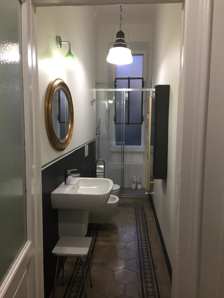 Aménagement d'une petite salle de bain rétro avec un placard à porte plane, des portes de placard grises, WC suspendus, carreaux de ciment au sol et un lavabo suspendu.