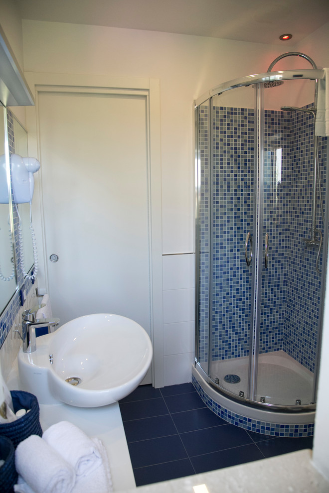 Inspiration pour une petite salle d'eau marine avec des portes de placard blanches, une douche d'angle, WC séparés, un carrelage bleu, des carreaux de porcelaine, un mur blanc, un sol en carrelage de porcelaine, une vasque, un plan de toilette en bois, un sol bleu, un placard à porte plane et une cabine de douche à porte coulissante.