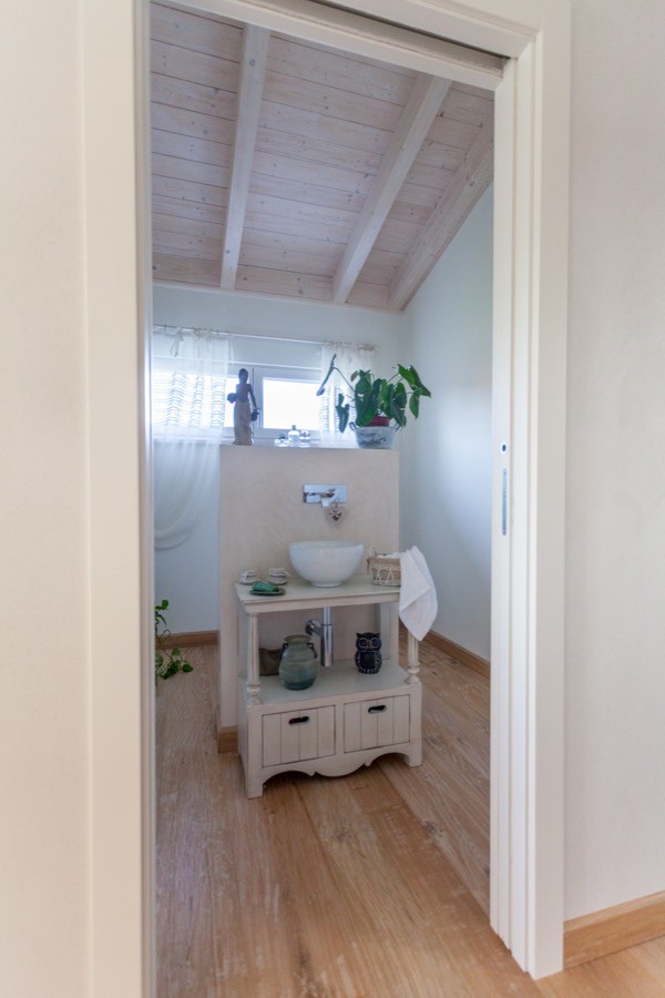 Großes Country Badezimmer En Suite mit freistehender Badewanne, beiger Wandfarbe, braunem Holzboden und braunem Boden in Sonstige