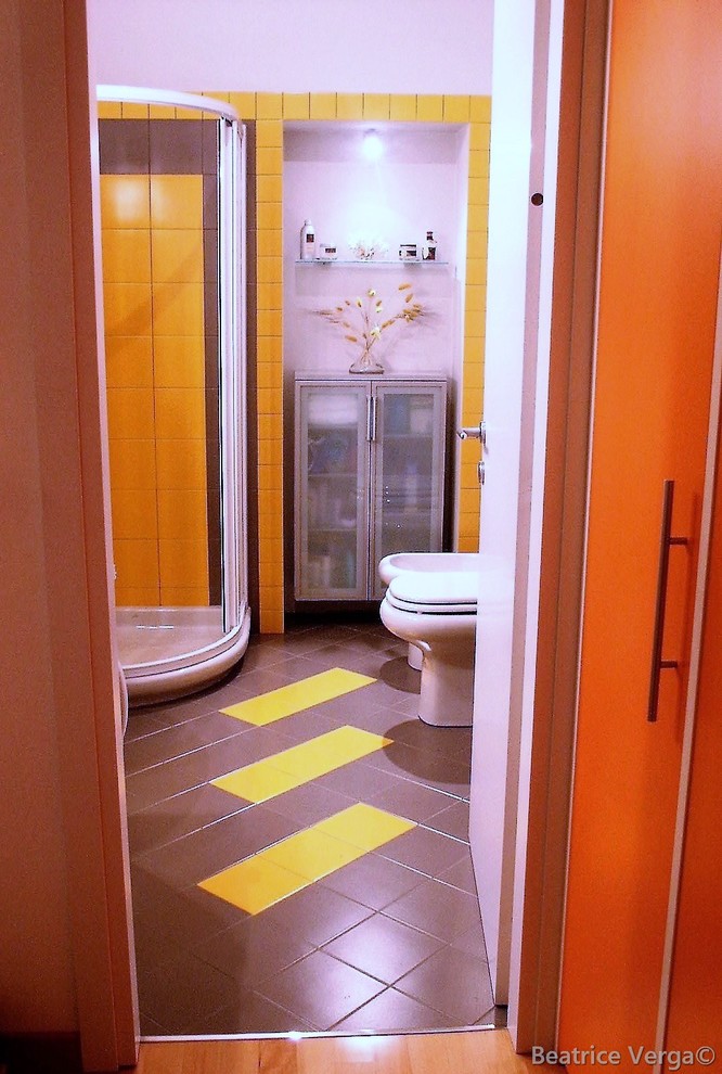Foto på ett litet funkis badrum med dusch, med släta luckor, vita skåp, en hörndusch, en toalettstol med hel cisternkåpa, gul kakel, keramikplattor, vita väggar, klinkergolv i porslin och ett konsol handfat