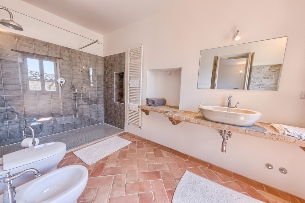 На фото: главная ванная комната среднего размера в средиземноморском стиле с душем без бортиков, инсталляцией, керамической плиткой, полом из терракотовой плитки и настольной раковиной с