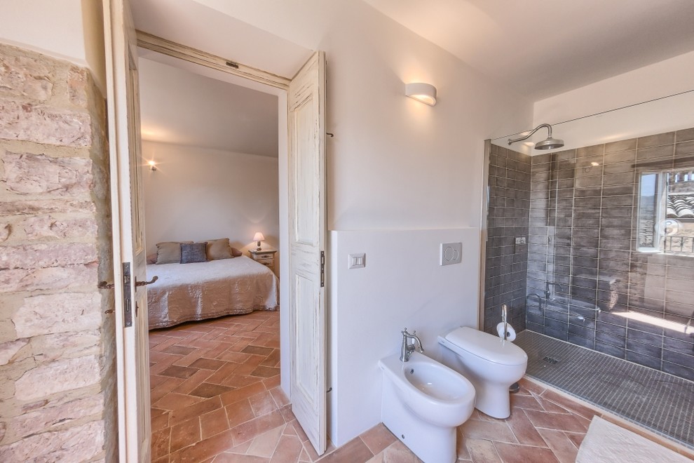 Idéer för mellanstora medelhavsstil en-suite badrum, med en kantlös dusch, en vägghängd toalettstol, keramikplattor, klinkergolv i terrakotta och ett fristående handfat