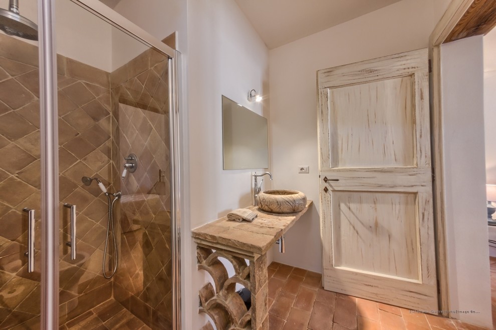 Inredning av ett medelhavsstil mellanstort badrum med dusch, med en kantlös dusch, en vägghängd toalettstol, perrakottakakel, klinkergolv i terrakotta och ett fristående handfat