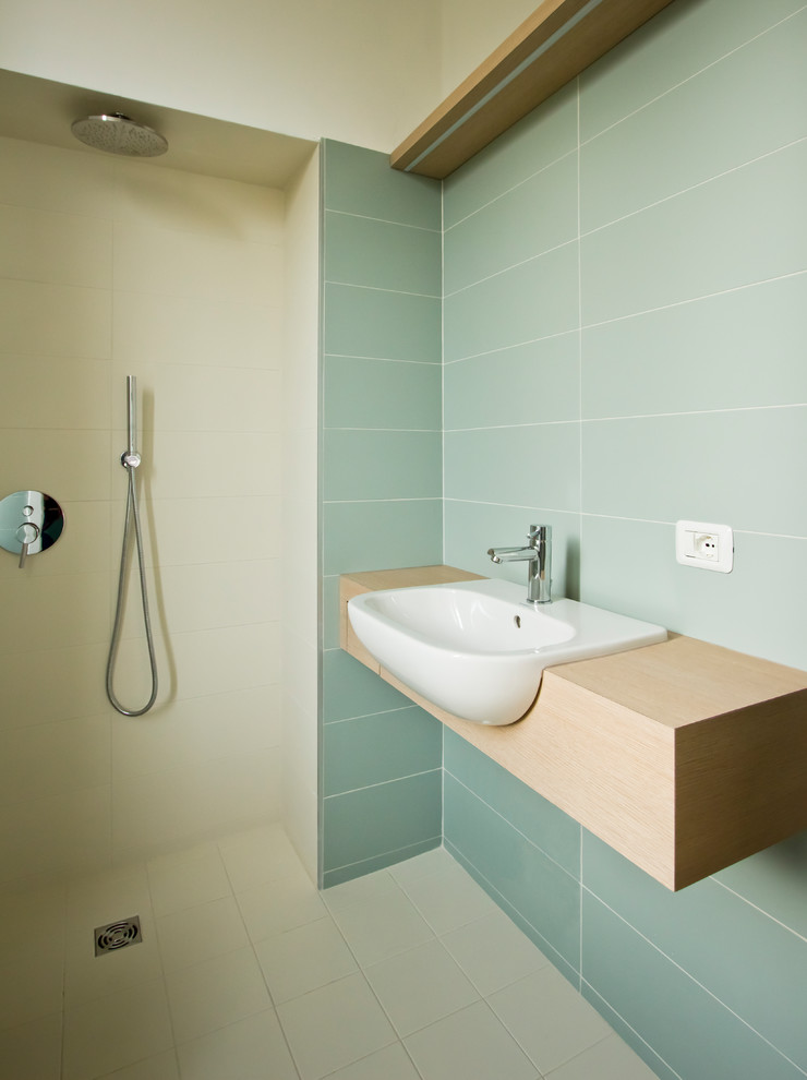 Small scandi shower room bathroom in Milan with open cabinets, light wood cabinets, a built-in shower, a wall mounted toilet, green tiles, porcelain tiles, green walls, porcelain flooring, an integrated sink, wooden worktops, grey floors, an open shower and brown worktops.