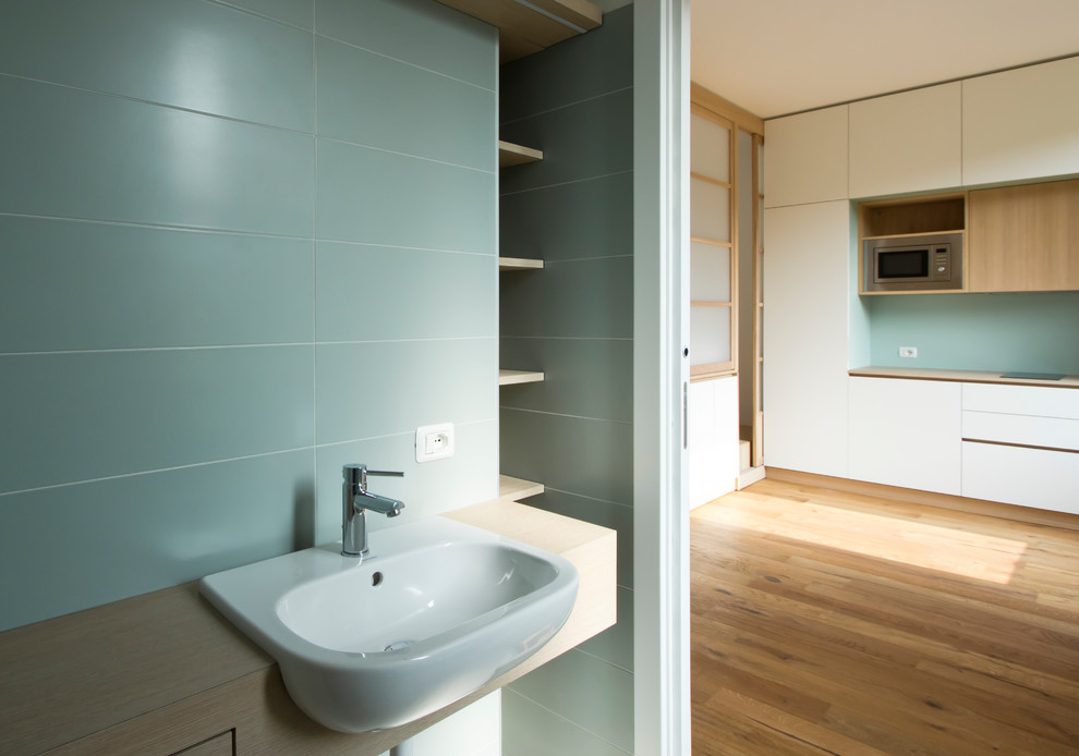 Пример оригинального дизайна: маленькая ванная комната в скандинавском стиле с открытыми фасадами, светлыми деревянными фасадами, душем без бортиков, инсталляцией, зеленой плиткой, керамогранитной плиткой, зелеными стенами, полом из керамогранита, душевой кабиной, монолитной раковиной, столешницей из дерева, серым полом, открытым душем и коричневой столешницей для на участке и в саду