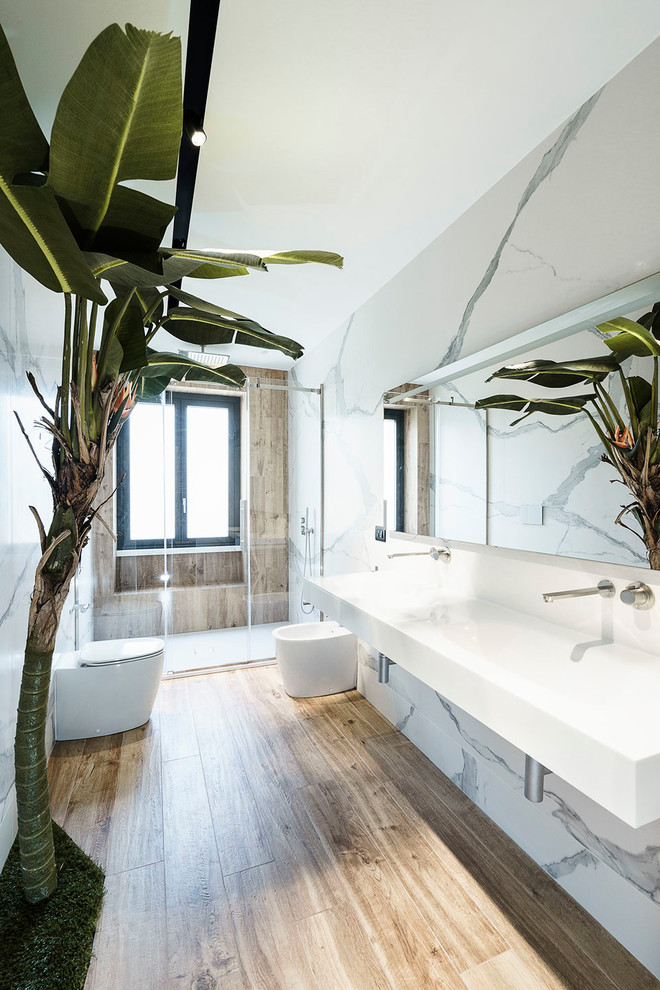 Идея дизайна: большая главная ванная комната в современном стиле с белой плиткой, мраморной плиткой, душем в нише, биде, белыми стенами, полом из керамогранита, подвесной раковиной, коричневым полом и душем с распашными дверями