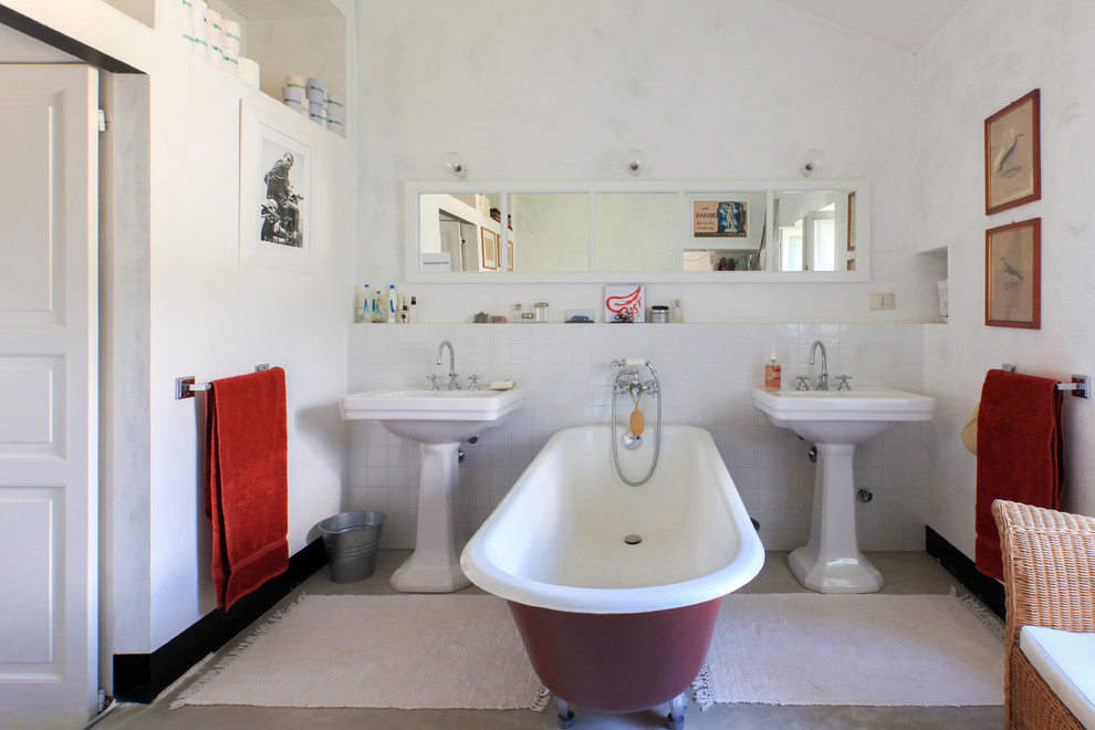 Immagine di una stanza da bagno padronale mediterranea con vasca freestanding, piastrelle bianche, pareti bianche, pavimento in cemento, lavabo a colonna e pavimento grigio