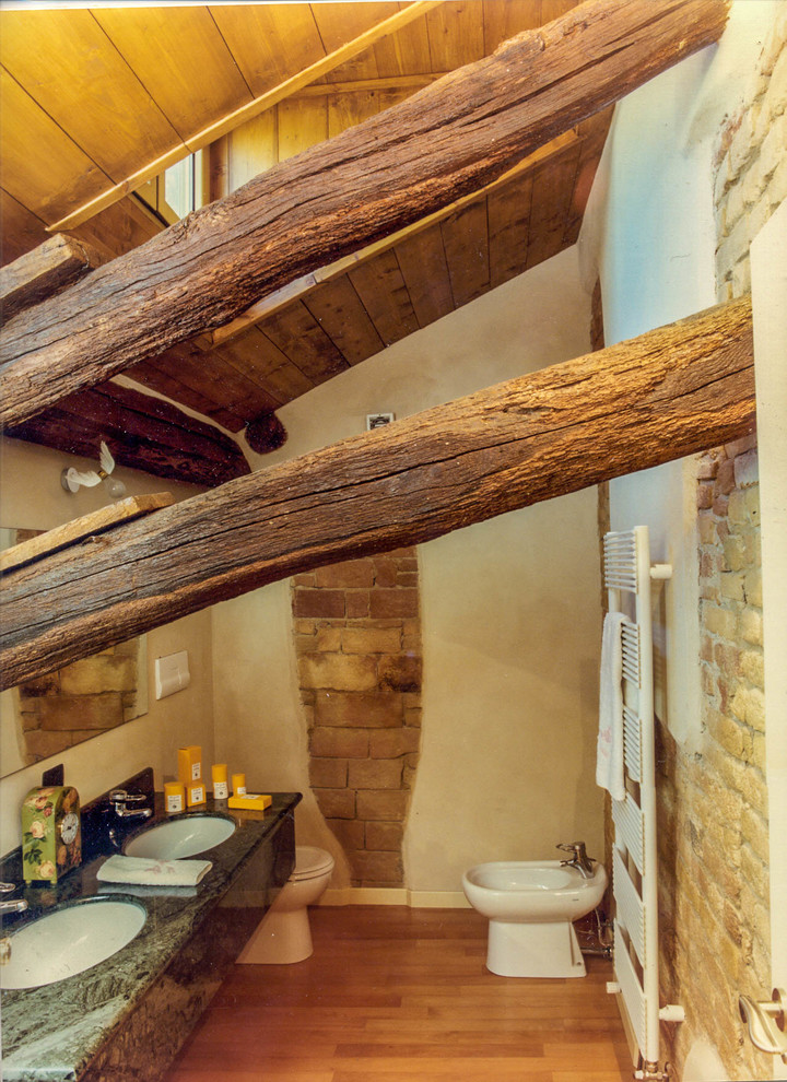 Kleines Landhaus Badezimmer mit Toilette mit Aufsatzspülkasten, beiger Wandfarbe, braunem Holzboden und Einbauwaschbecken in Mailand