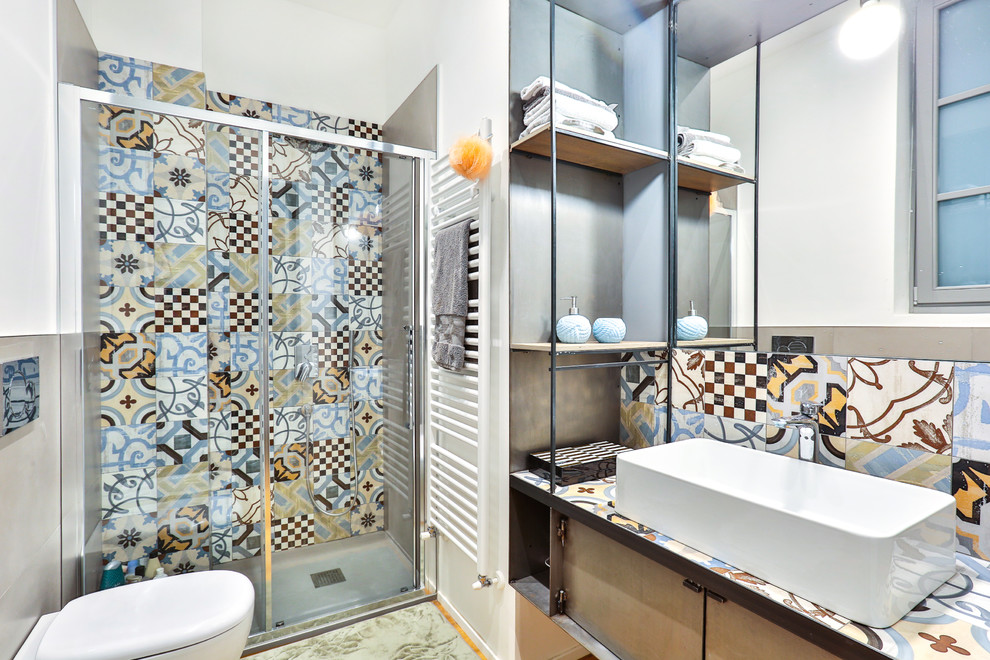 Cette image montre une salle d'eau méditerranéenne de taille moyenne avec une douche d'angle, un carrelage multicolore, des carreaux de céramique, un mur blanc, une vasque et une cabine de douche à porte coulissante.