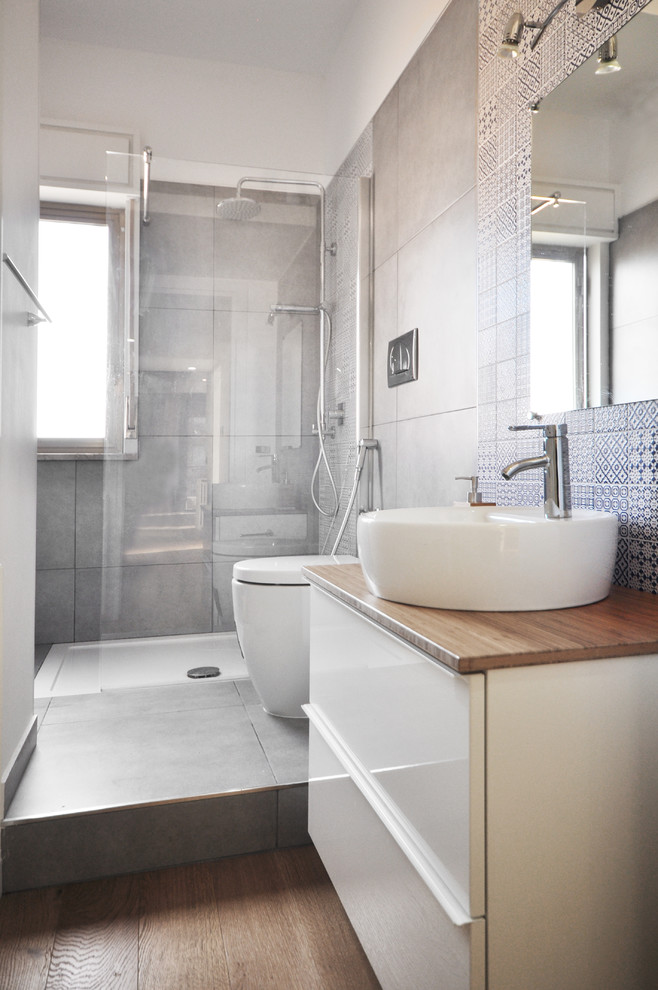 Idéer för ett mellanstort modernt badrum med dusch, med släta luckor, vita skåp, en hörndusch, blå kakel, grå kakel, vita väggar, mellanmörkt trägolv, ett fristående handfat, träbänkskiva och med dusch som är öppen