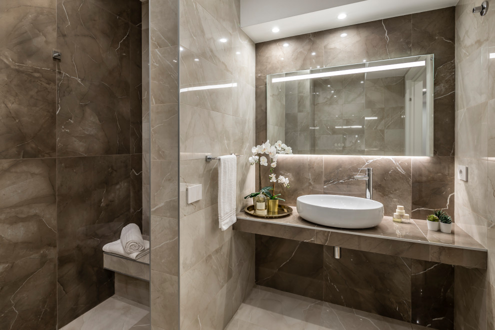 Modern ensuite bathroom in Milan with an alcove bath, an alcove shower, a wall mounted toilet, beige tiles, porcelain tiles, beige walls, porcelain flooring, a vessel sink, tiled worktops, an open shower, brown worktops, a shower bench, a single sink and a floating vanity unit.