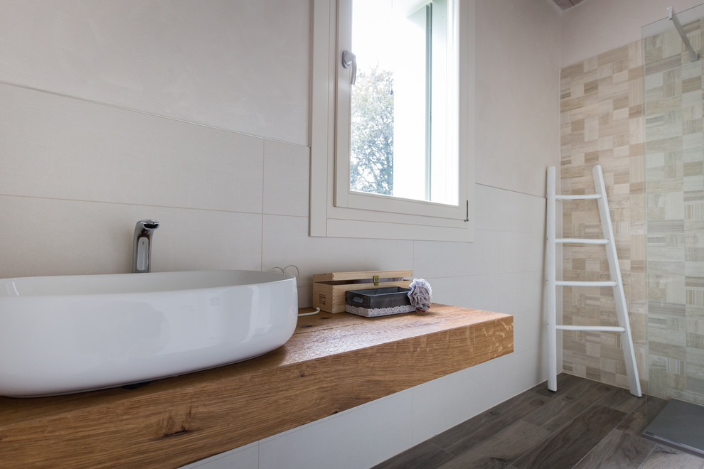 Modern inredning av ett badrum med dusch, med skåp i slitet trä, en öppen dusch, en vägghängd toalettstol, beige kakel, keramikplattor, beige väggar, klinkergolv i porslin, ett fristående handfat och träbänkskiva