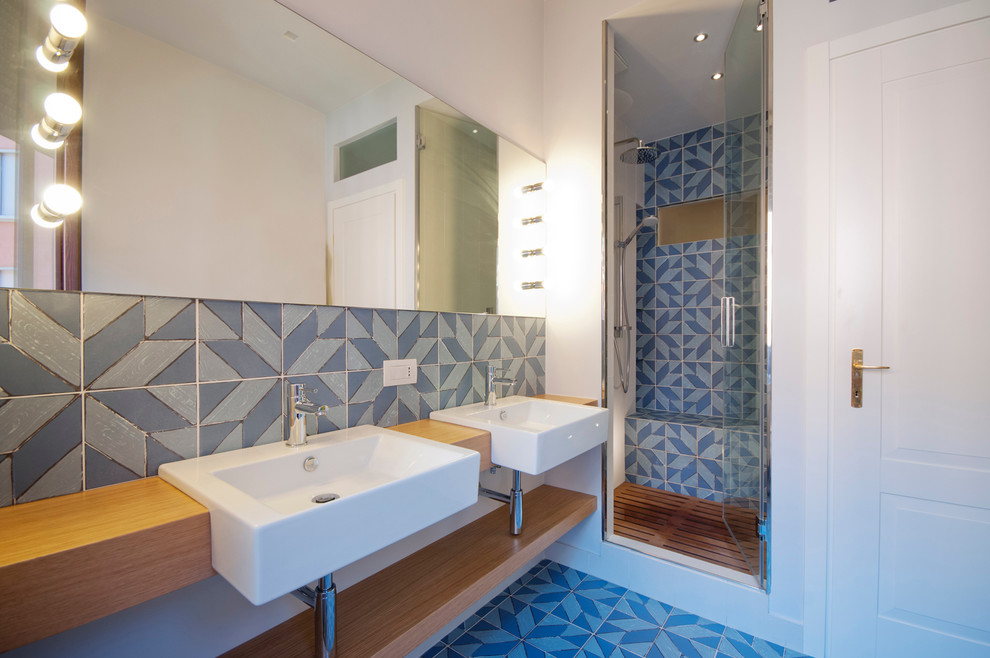 Пример оригинального дизайна: ванная комната среднего размера в морском стиле с светлыми деревянными фасадами, душем в нише, разноцветной плиткой, керамической плиткой, белыми стенами, полом из керамической плитки, душевой кабиной, раковиной с несколькими смесителями, столешницей из дерева и душем с распашными дверями