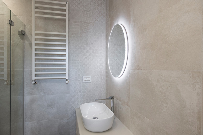Example of a large cottage chic 3/4 ceramic tile and multicolored tile porcelain tile and brown floor corner shower design in Rome with a wall-mount toilet, white walls, a vessel sink, a hinged shower door, flat-panel cabinets, beige cabinets and beige countertops