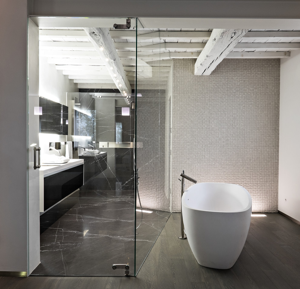Стильный дизайн: большая главная ванная комната в современном стиле с плоскими фасадами, черными фасадами, отдельно стоящей ванной, душем над ванной, серыми стенами, деревянным полом, раковиной с несколькими смесителями и черным полом - последний тренд