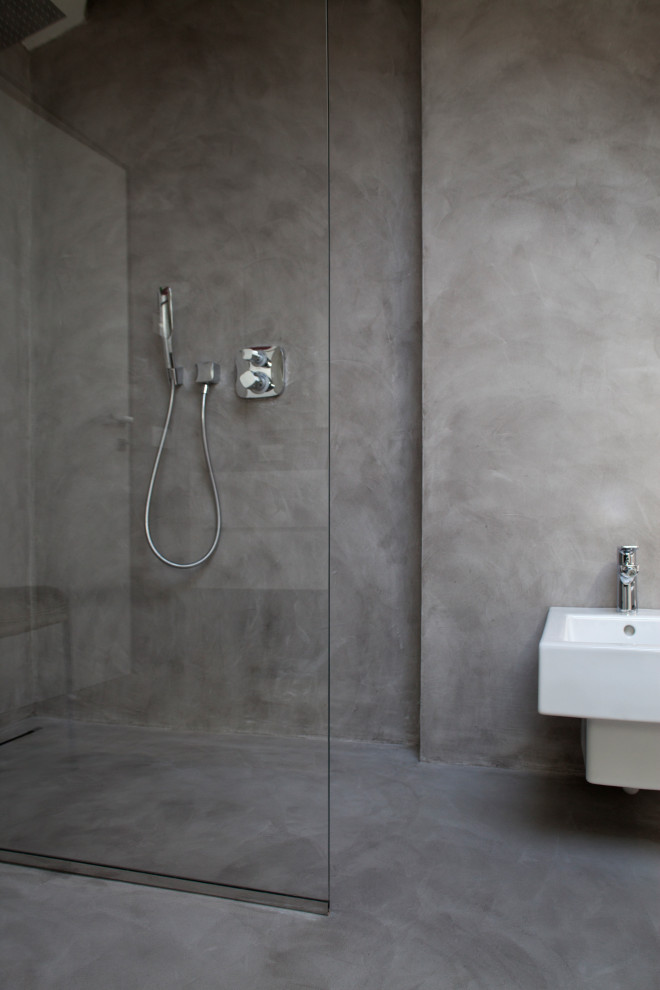 Exempel på ett mellanstort modernt vit vitt en-suite badrum, med släta luckor, vita skåp, en kantlös dusch, en vägghängd toalettstol, grå väggar, ett väggmonterat handfat, bänkskiva i akrylsten och med dusch som är öppen
