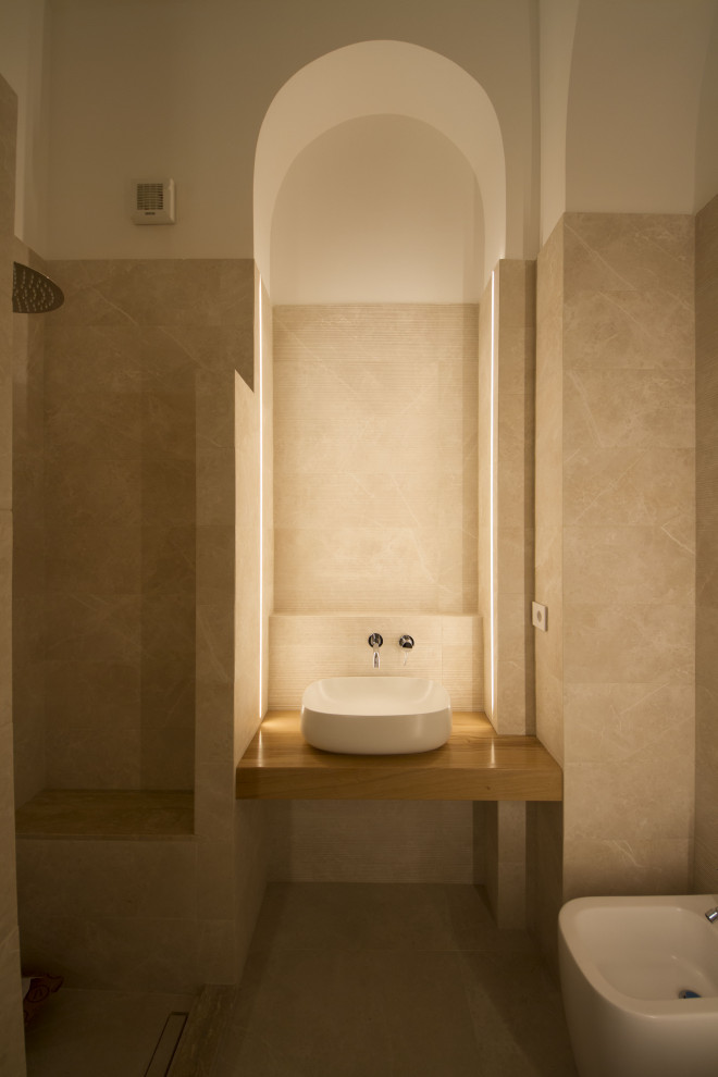Foto på ett litet funkis beige badrum med dusch, med en öppen dusch, en vägghängd toalettstol, beige kakel, porslinskakel, vita väggar, ett fristående handfat, träbänkskiva och beiget golv