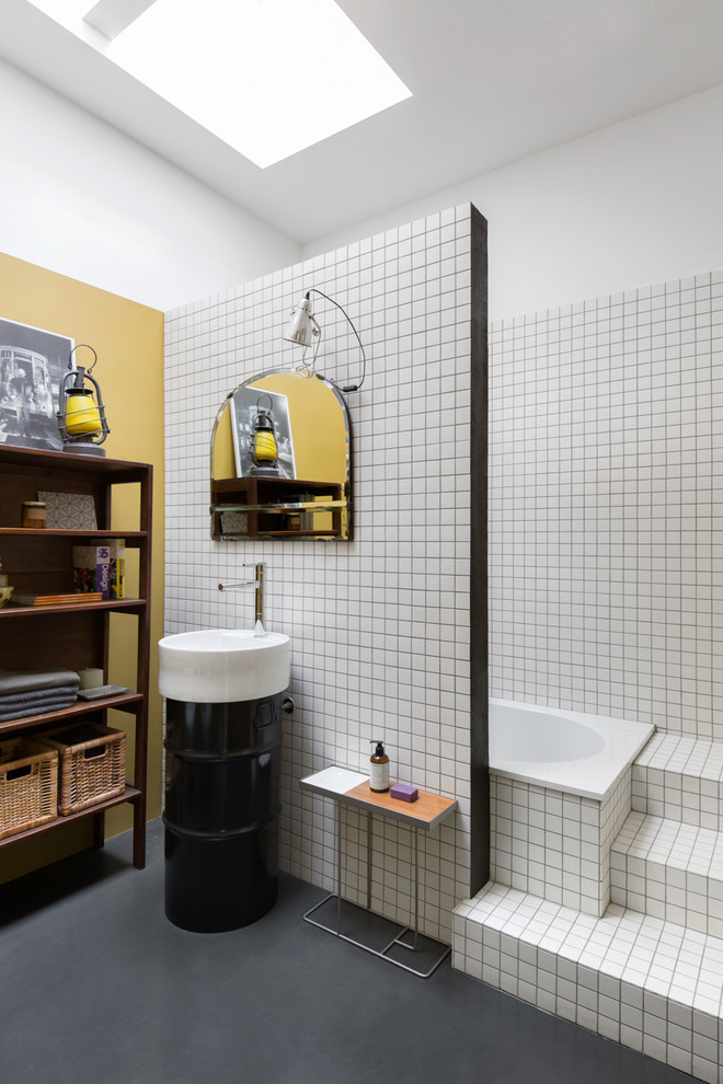 Mittelgroßes Industrial Badezimmer mit schwarzen Schränken, Einbaubadewanne, weißen Fliesen, Keramikfliesen, weißer Wandfarbe, Betonboden, Sockelwaschbecken und grauem Boden in Mailand