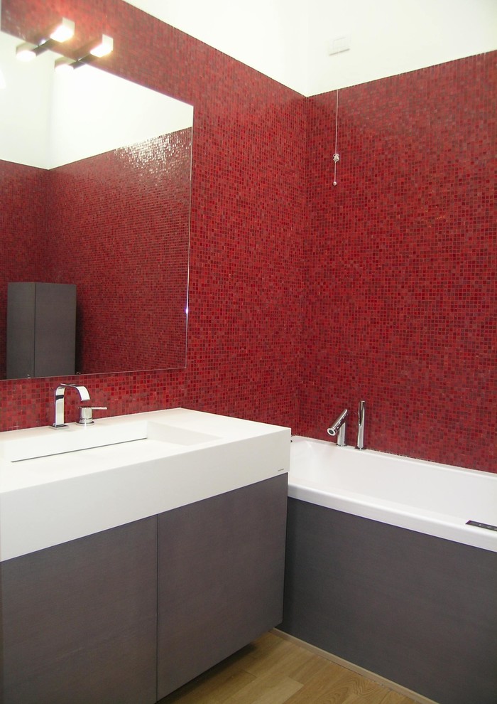 Idéer för ett stort modernt badrum, med släta luckor, skåp i mörkt trä, ett fristående badkar, en toalettstol med separat cisternkåpa, röd kakel, mosaik, vita väggar, mellanmörkt trägolv, ett integrerad handfat och bänkskiva i akrylsten