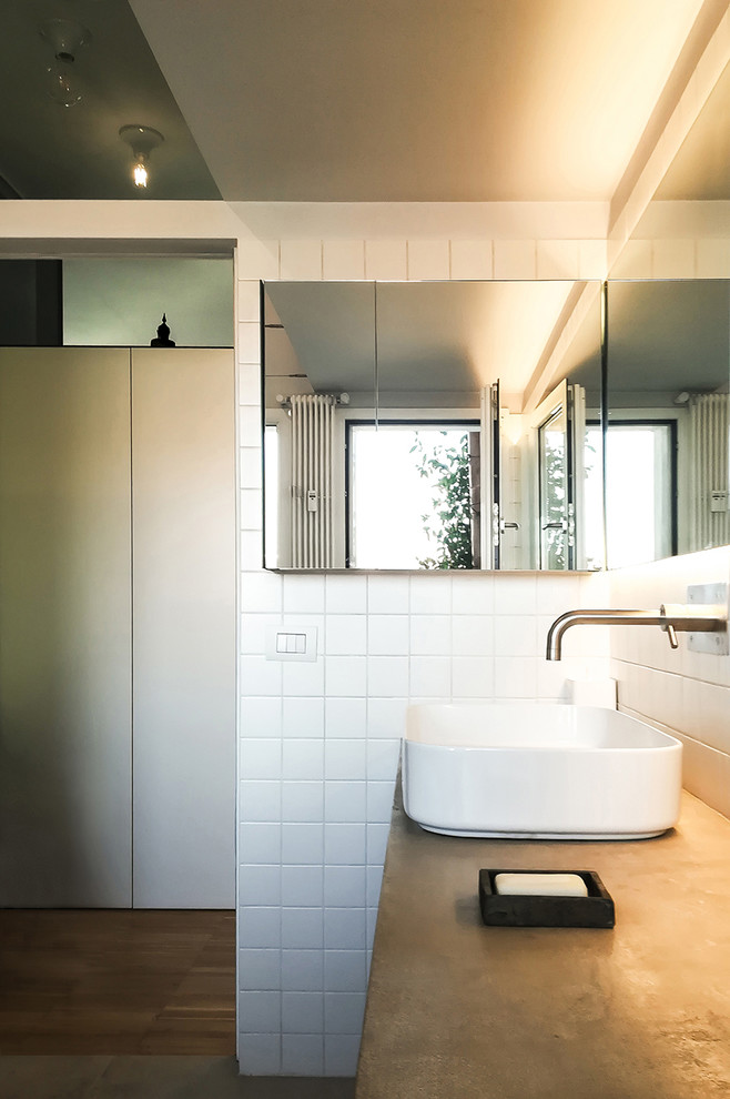 Modern inredning av ett mellanstort en-suite badrum, med släta luckor, ett platsbyggt badkar, en dusch/badkar-kombination, en vägghängd toalettstol, vit kakel, keramikplattor, vita väggar, ett fristående handfat, bänkskiva i betong och dusch med duschdraperi