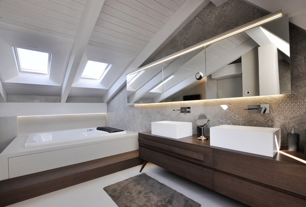 Idéer för funkis brunt en-suite badrum, med släta luckor, skåp i mörkt trä, ett platsbyggt badkar, grå kakel, grå väggar, ett fristående handfat, träbänkskiva och grått golv