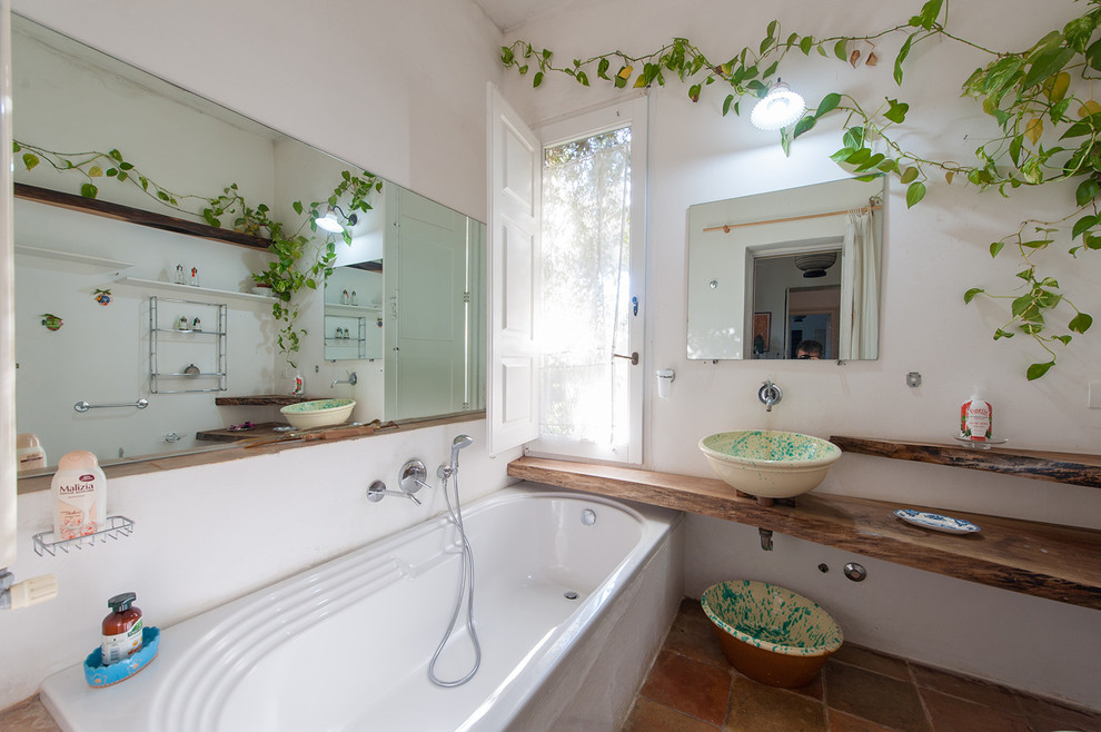 Inspiration for a mediterranean ensuite bathroom in Bari with open cabinets, a built-in bath, orange tiles, brown tiles, terracotta tiles, white walls, terracotta flooring, a vessel sink, wooden worktops, brown floors and brown worktops.