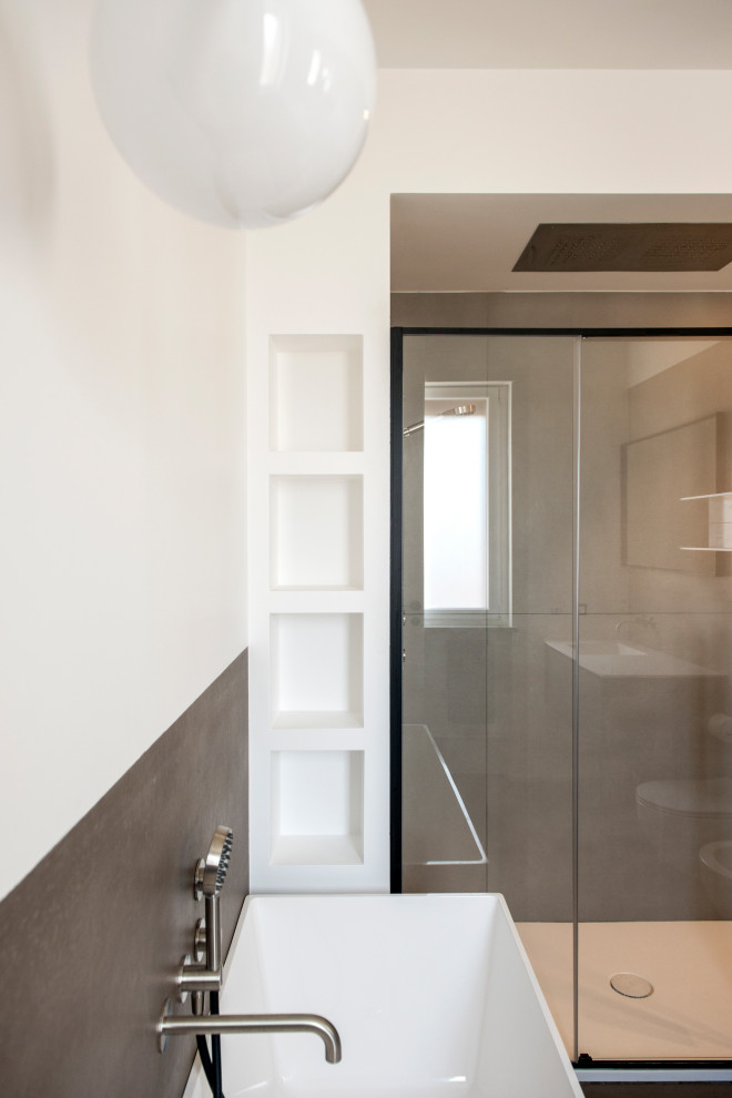 Пример оригинального дизайна: большая главная ванная комната в современном стиле с стеклянными фасадами, синими фасадами, отдельно стоящей ванной, душем над ванной, инсталляцией, белой плиткой, керамогранитной плиткой, белыми стенами, полом из керамогранита, монолитной раковиной, столешницей из искусственного камня, коричневым полом, душем с раздвижными дверями, белой столешницей, нишей, тумбой под одну раковину, подвесной тумбой и многоуровневым потолком