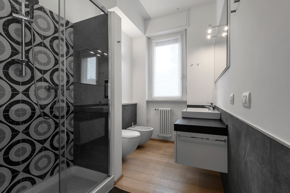 Inspiration för ett mellanstort funkis badrum med dusch, med vita skåp, en hörndusch, en vägghängd toalettstol, svart och vit kakel, keramikplattor, vita väggar, ett avlångt handfat, dusch med skjutdörr, klinkergolv i keramik och beiget golv