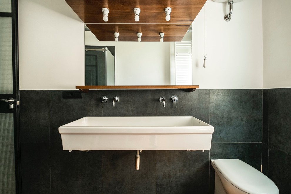 Photo of a small midcentury shower room bathroom in Rome with flat-panel cabinets, medium wood cabinets, a double shower, a two-piece toilet, black tiles, porcelain tiles, white walls, dark hardwood flooring and a vessel sink.