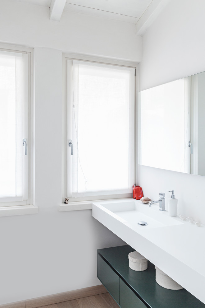 Exemple d'une salle de bain principale tendance avec un placard à porte plane, des portes de placards vertess, un mur blanc, parquet clair, un lavabo intégré, un plan de toilette en surface solide et un plan de toilette blanc.