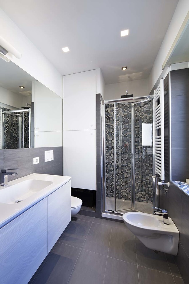 Idee per una stanza da bagno con doccia minimal di medie dimensioni con ante lisce, ante in legno chiaro, doccia ad angolo, WC sospeso, piastrelle grigie, piastrelle in gres porcellanato, pareti bianche, pavimento in gres porcellanato e lavabo integrato