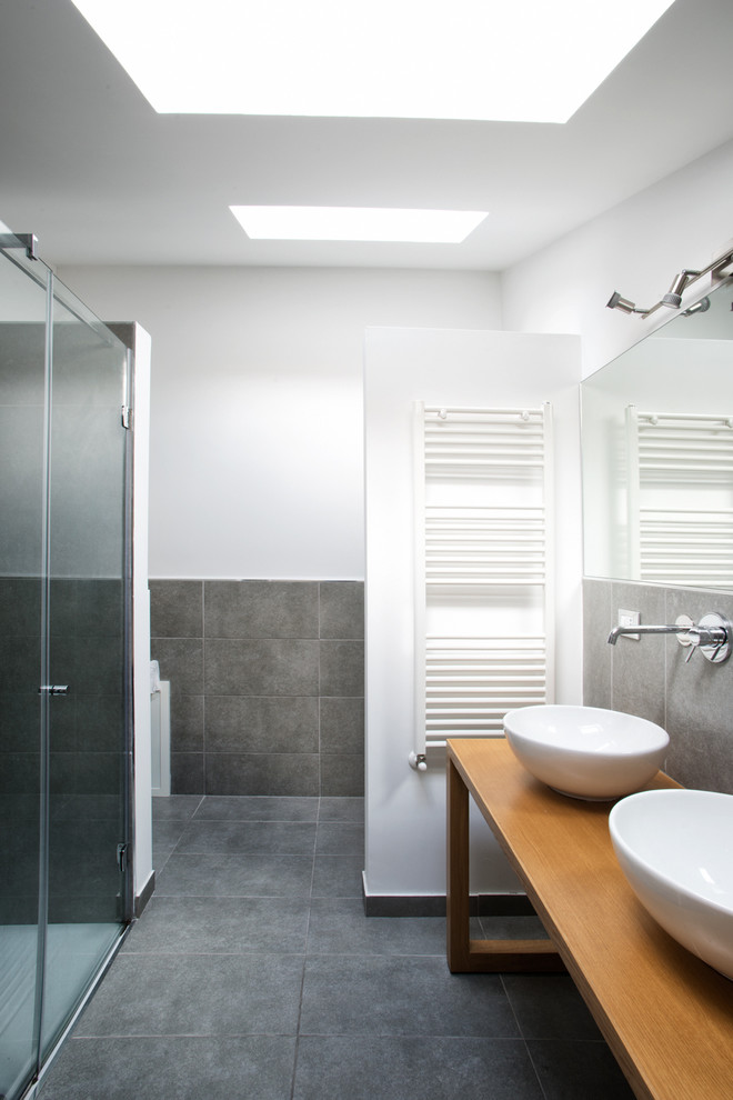 На фото: ванная комната среднего размера в современном стиле с серой плиткой, керамогранитной плиткой, белыми стенами, полом из керамогранита, настольной раковиной, столешницей из дерева и серым полом