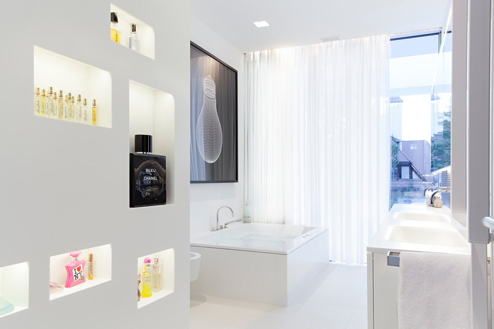 Réalisation d'une salle de bain design avec une baignoire indépendante, un mur blanc et un lavabo intégré.