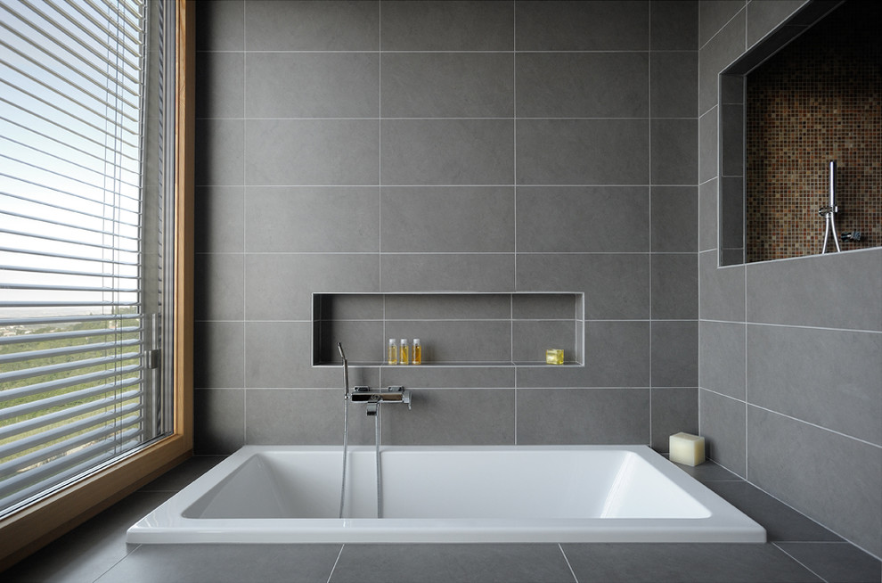 Inspiration pour une grande salle de bain principale design avec une baignoire posée, un carrelage gris et un sol en carrelage de céramique.