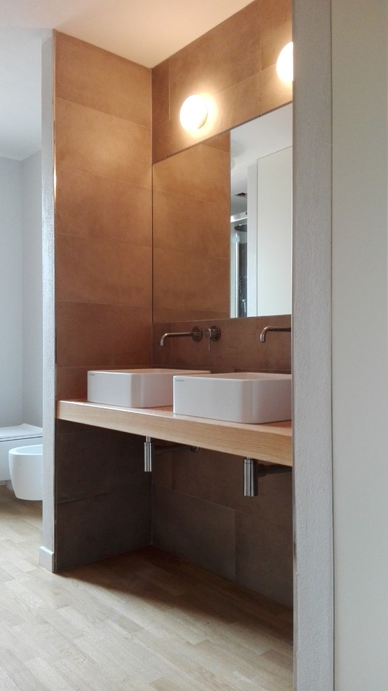 Esempio di una stanza da bagno con doccia minimalista di medie dimensioni con ante lisce, ante bianche, WC sospeso, piastrelle in gres porcellanato, pareti grigie, parquet chiaro, lavabo a consolle e top in legno