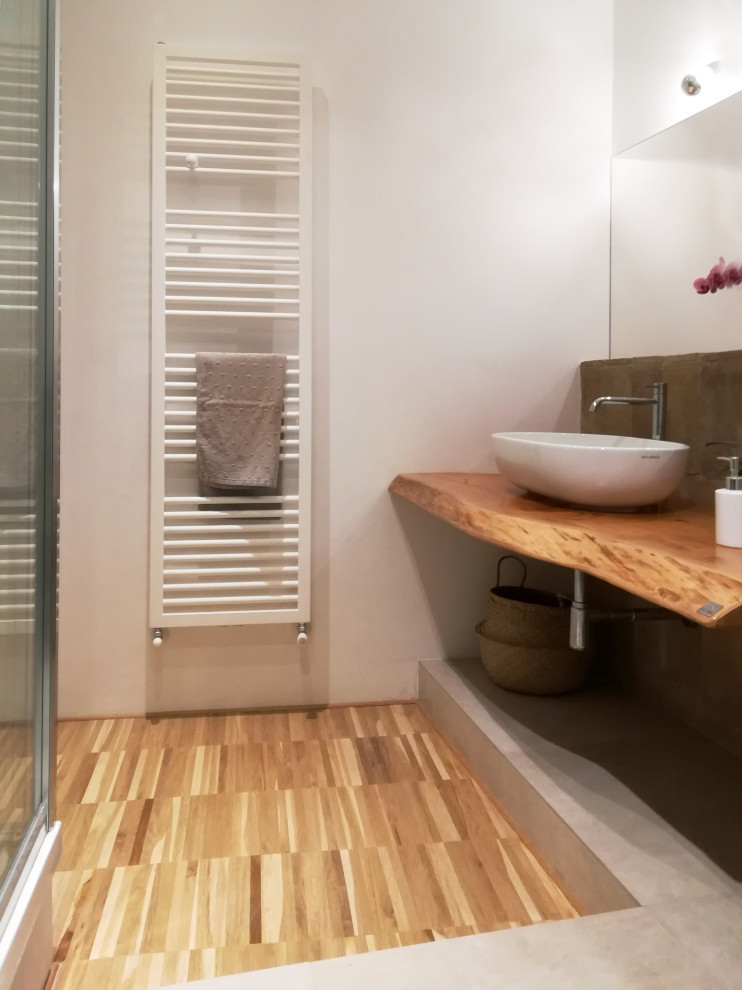Eklektisk inredning av ett litet brun brunt badrum med dusch, med skåp i ljust trä, en öppen dusch, en toalettstol med separat cisternkåpa, porslinskakel, vita väggar, mörkt trägolv, ett fristående handfat, träbänkskiva, brunt golv och dusch med skjutdörr