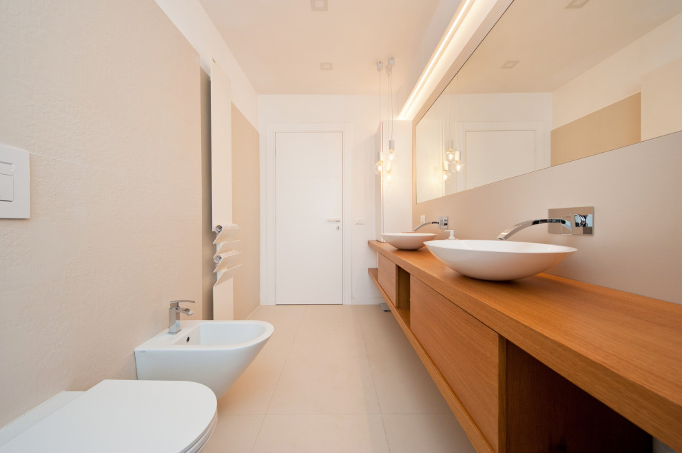 Immagine di una grande stanza da bagno con doccia minimal con ante lisce, ante marroni, WC sospeso, piastrelle beige, piastrelle in gres porcellanato, pareti bianche, pavimento in gres porcellanato, lavabo a bacinella, top in legno, pavimento beige, top marrone, due lavabi e mobile bagno sospeso