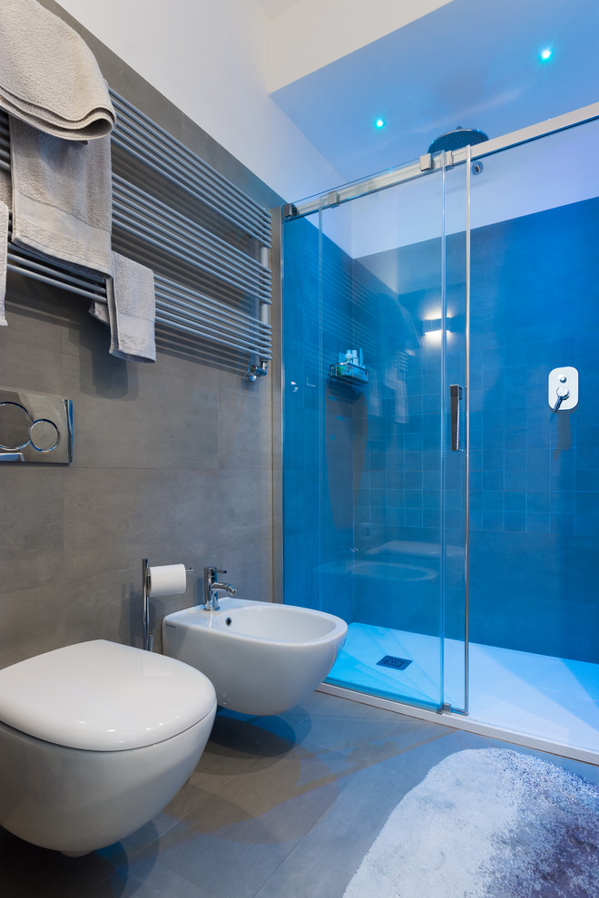 Inspiration for a medium sized contemporary shower room bathroom in Bologna with an alcove shower, a wall mounted toilet, grey tiles, porcelain tiles, grey walls, porcelain flooring and grey floors.