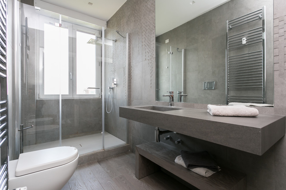 Inredning av ett modernt mellanstort en-suite badrum, med öppna hyllor, en dusch i en alkov, en toalettstol med hel cisternkåpa, grå kakel, grå väggar, ett integrerad handfat och dusch med gångjärnsdörr