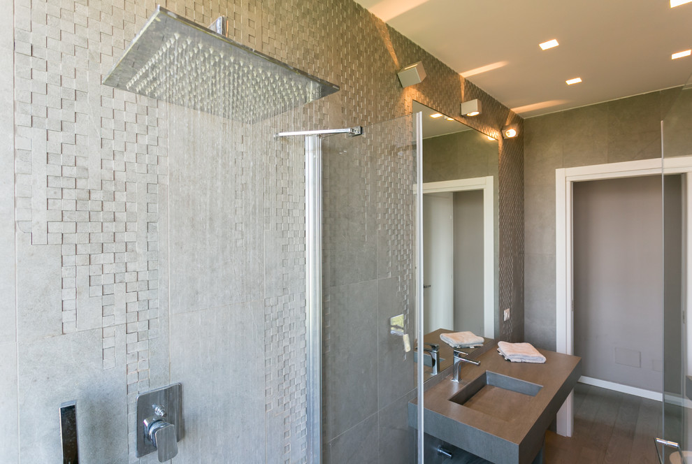 Foto de cuarto de baño principal contemporáneo de tamaño medio con armarios abiertos, ducha empotrada, sanitario de una pieza, baldosas y/o azulejos grises, paredes grises, lavabo integrado y ducha con puerta con bisagras